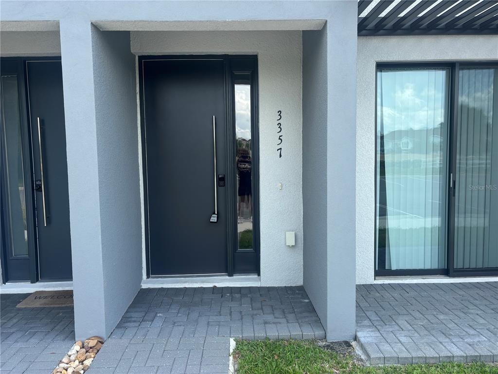 The exterior entrance features a dark modern door with a long handle and house number 3357 — 3357 TRANQUIL TRAIL, KISSIMMEE, FL