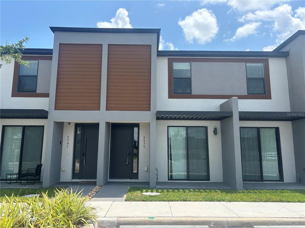 The exterior of a modern two-story townhouse features a mix of stucco and wood-look siding — 3357 TRANQUIL TRAIL, KISSIMMEE, FL