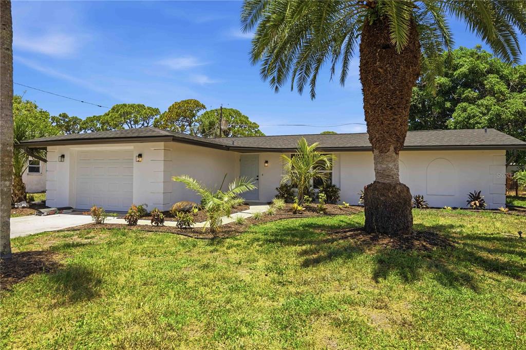 A single-story white house with a garage and a large palm tree in the yard — 386 CABANA ROAD, VENICE, FL