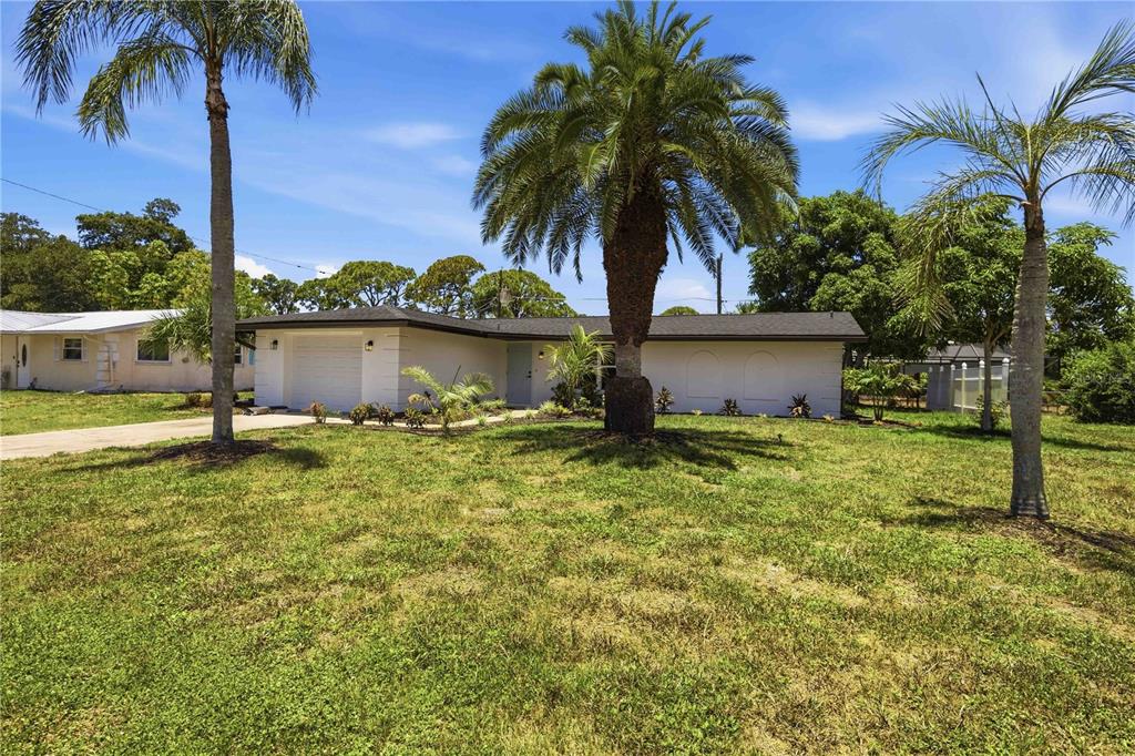 A single-story white house with a garage and palm trees sits on a grassy lot — 386 CABANA ROAD, VENICE, FL