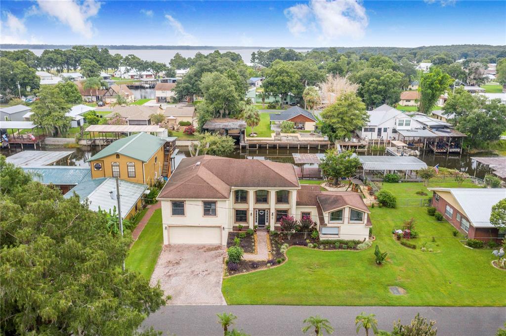 An aerial view shows a two-story house with a brown roof and a waterfront backyard — 55 PERCH STREET, HAINES CITY, FL