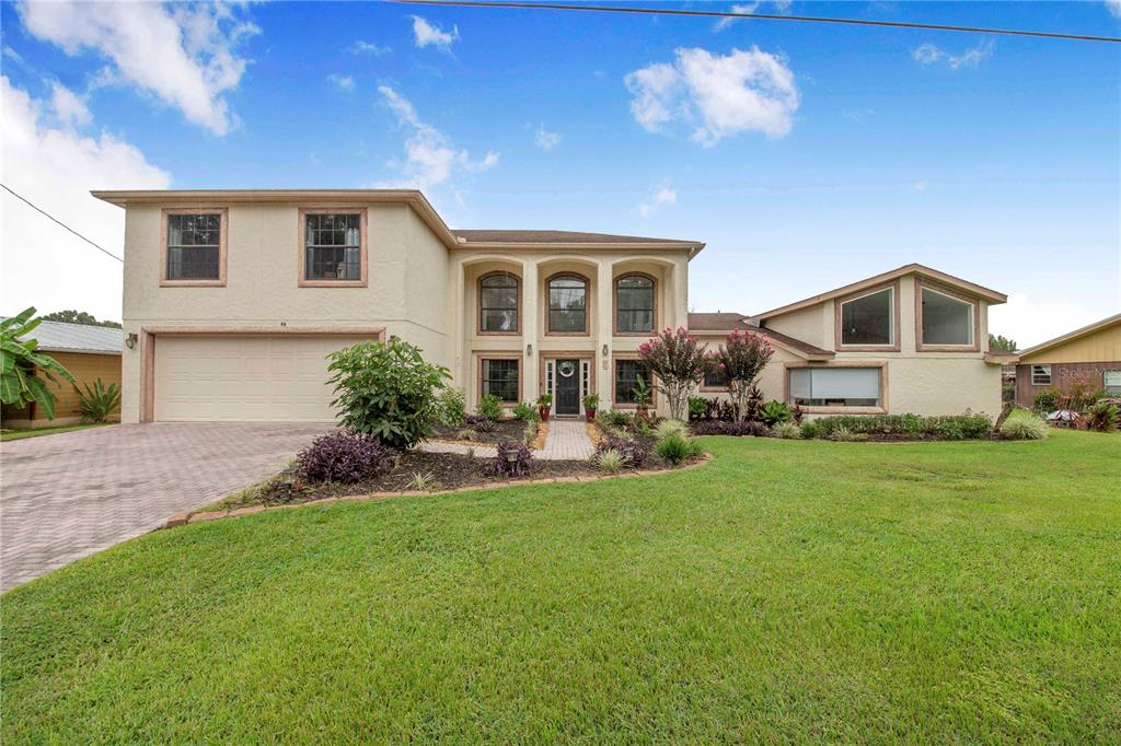 A two-story house with a beige stucco exterior, a two-car garage, and a large lawn — 55 PERCH STREET, HAINES CITY, FL