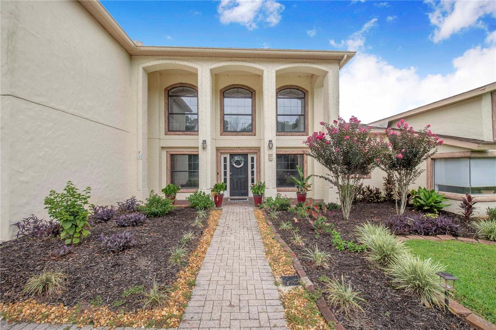 A two-story house exterior features a stone walkway leading to a dark front door — 55 PERCH STREET, HAINES CITY, FL