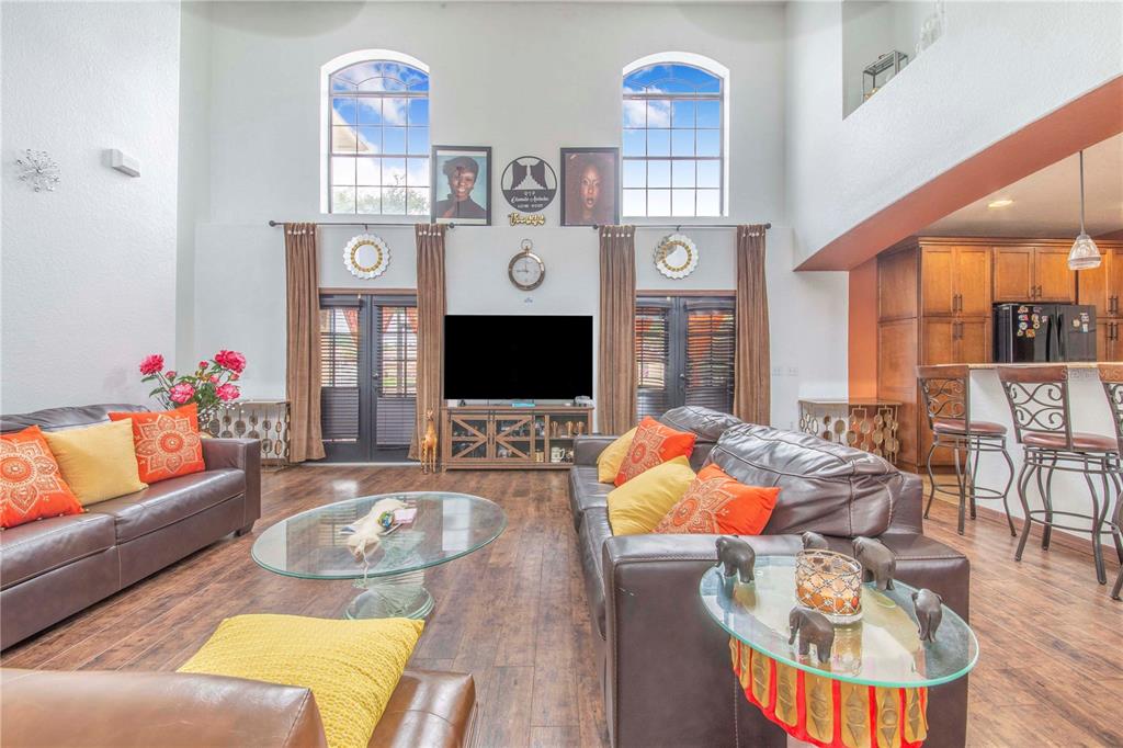 A living room with high ceilings, two leather sofas, a glass coffee table, and windows — 55 PERCH STREET, HAINES CITY, FL