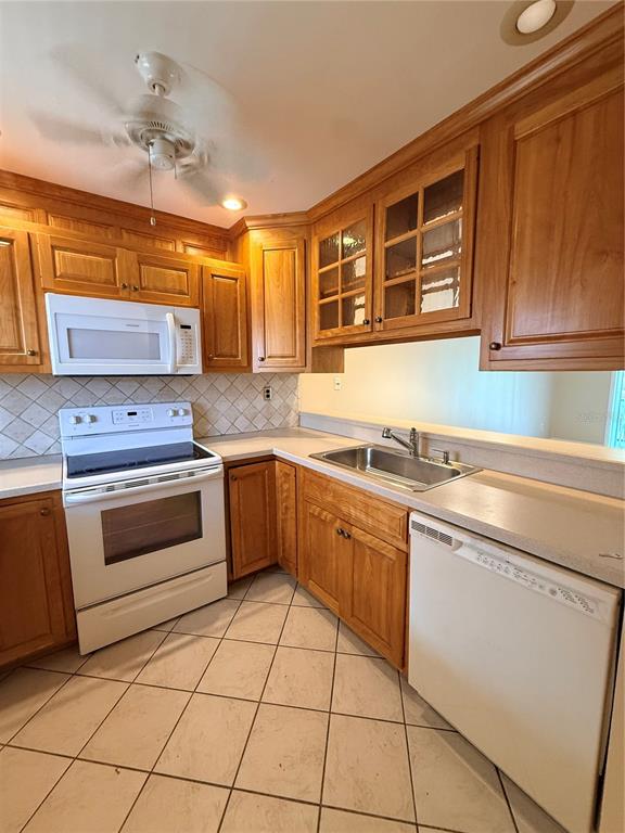 A kitchen features wood cabinets, a white stove, a microwave, and a tiled floor — 100 E KENTUCKY AVENUE UNIT A106, DELAND, FL