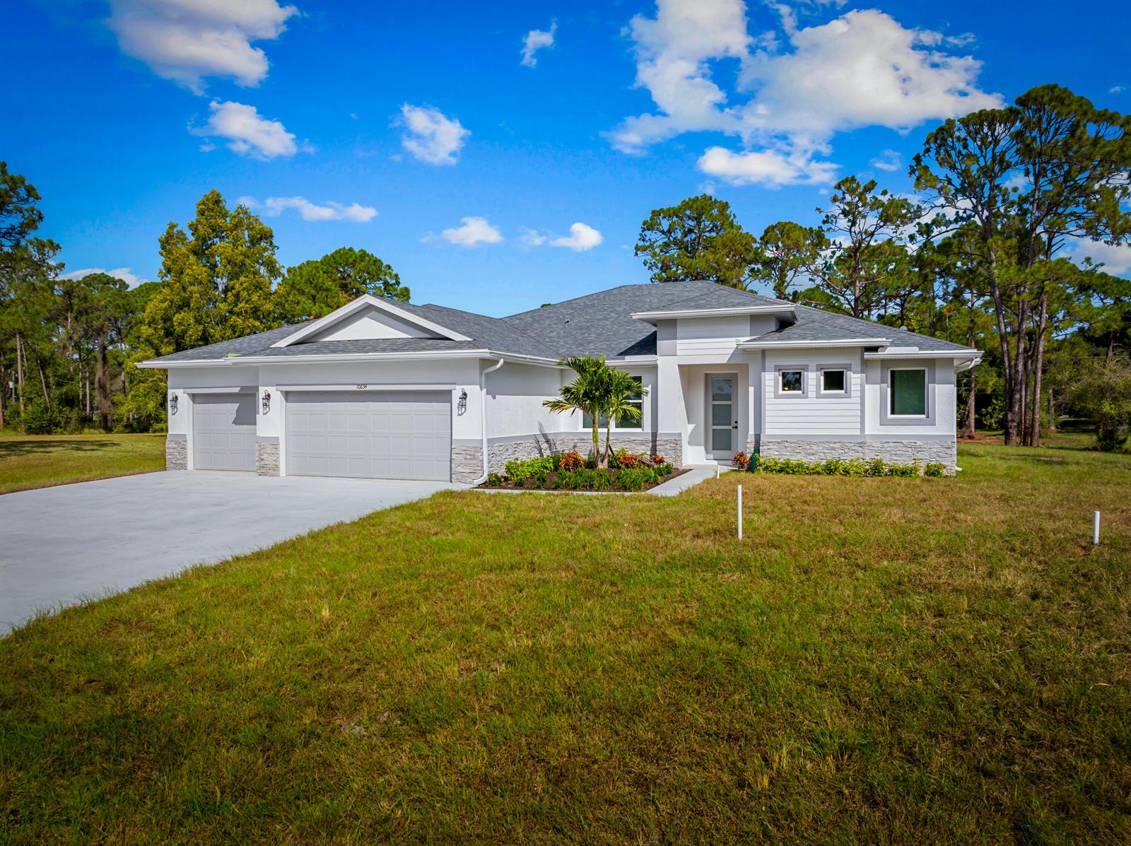 A single-story house with a gray shingled roof, white stucco walls, and a stone facade — 17521 N 76th St Street N, FL 33470, FL
