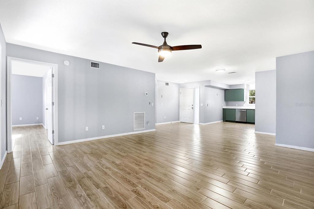 An open-concept living room features light gray walls, wood-look tile flooring, and a ceiling fan — 107 47TH AVENUE N, ST PETERSBURG, FL