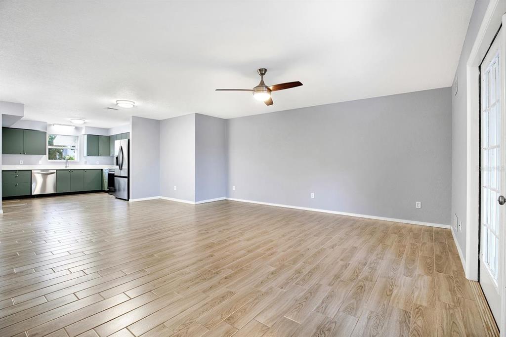 An open-concept living area with light wood-look tile flooring and a kitchen with green cabinets — 107 47TH AVENUE N, ST PETERSBURG, FL