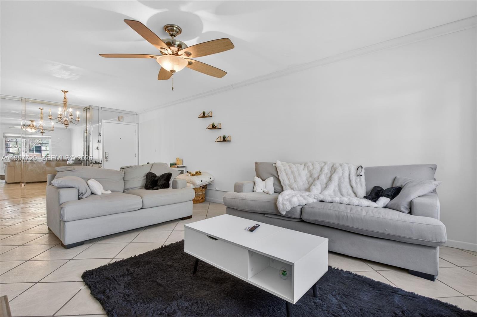 A living room features two gray sofas, a white coffee table, and a ceiling fan — 9 NE 19th Ct # 104C, Wilton Manors FL 33305, WILTON MANORS, FL