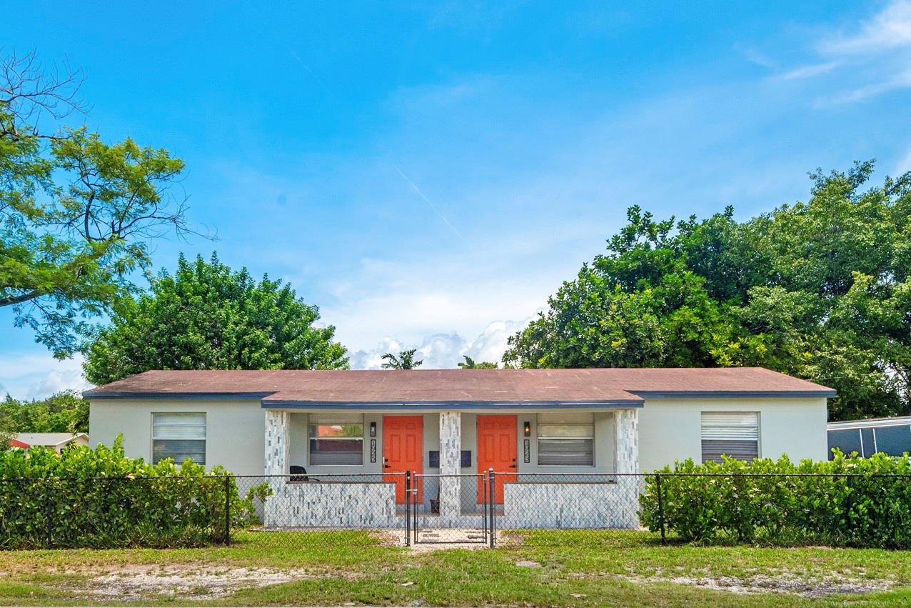 A single-story duplex with two orange front doors and a chain-link fence in front — 1923 N 23rd Avenue, Hollywood FL 33020, HOLLYWOOD, FL