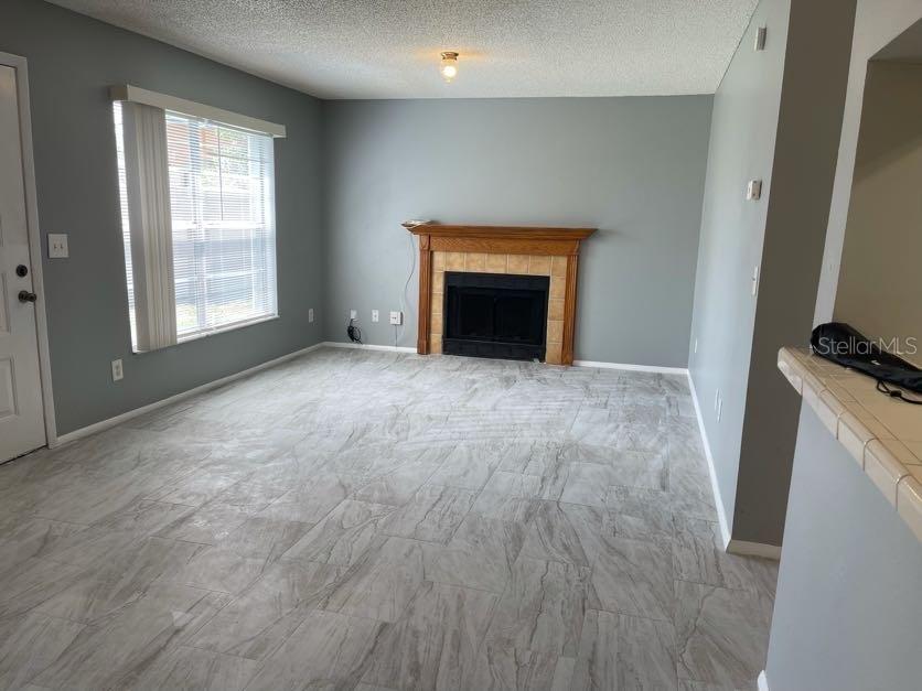 A living room features gray tile flooring, a fireplace with a wood mantel, and windows — 1004 NORTHLAKE DRIVE UNIT 1004, SANFORD, FL