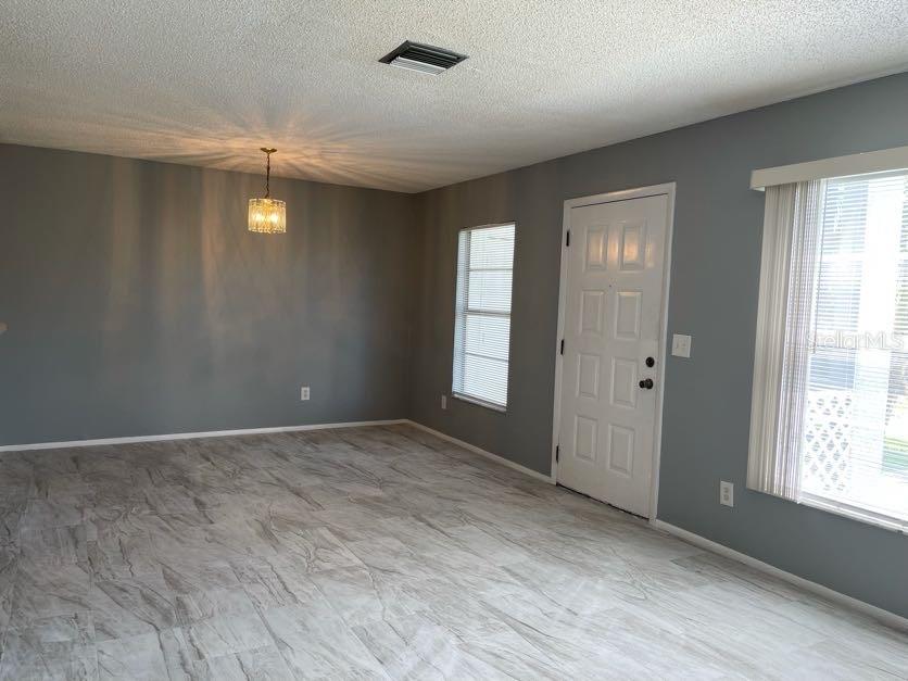 A room with gray walls, light-colored tile flooring, a chandelier, and a white entry door — 1004 NORTHLAKE DRIVE UNIT 1004, SANFORD, FL