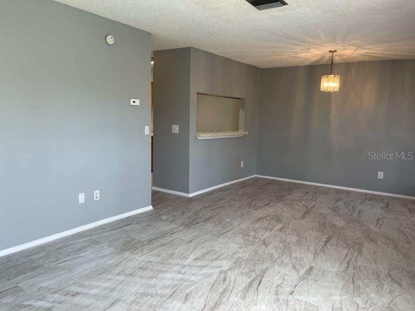 An empty room with gray walls, light-colored tile flooring, and a kitchen pass-through window — 1004 NORTHLAKE DRIVE UNIT 1004, SANFORD, FL