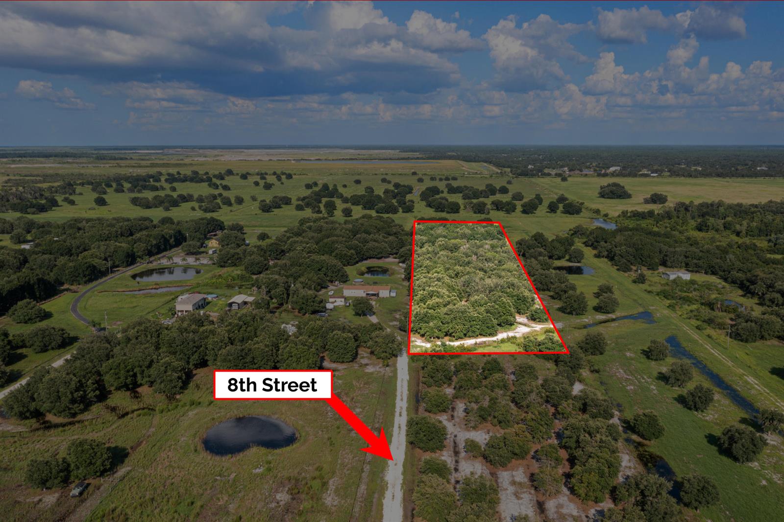An aerial view shows a rectangular wooded lot outlined in red next to a dirt road — 38203 8th Street E, FL 34251, FL