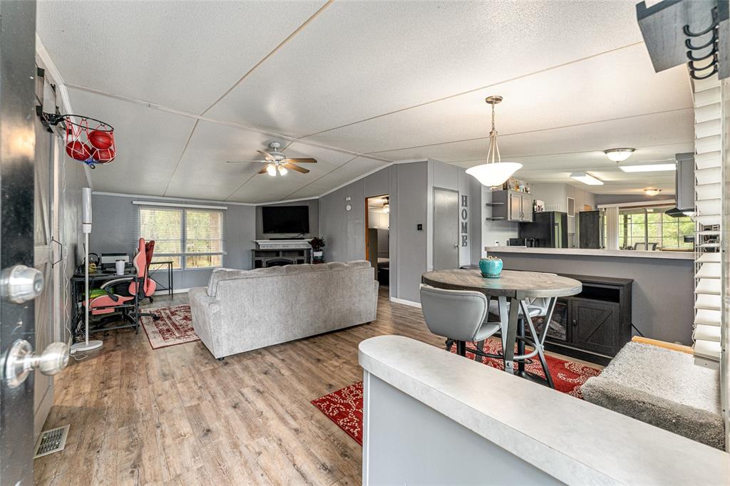 A living room and dining area feature light wood-look flooring, gray walls, and a ceiling fan — 1504 NW 156TH AVENUE, GAINESVILLE, FL