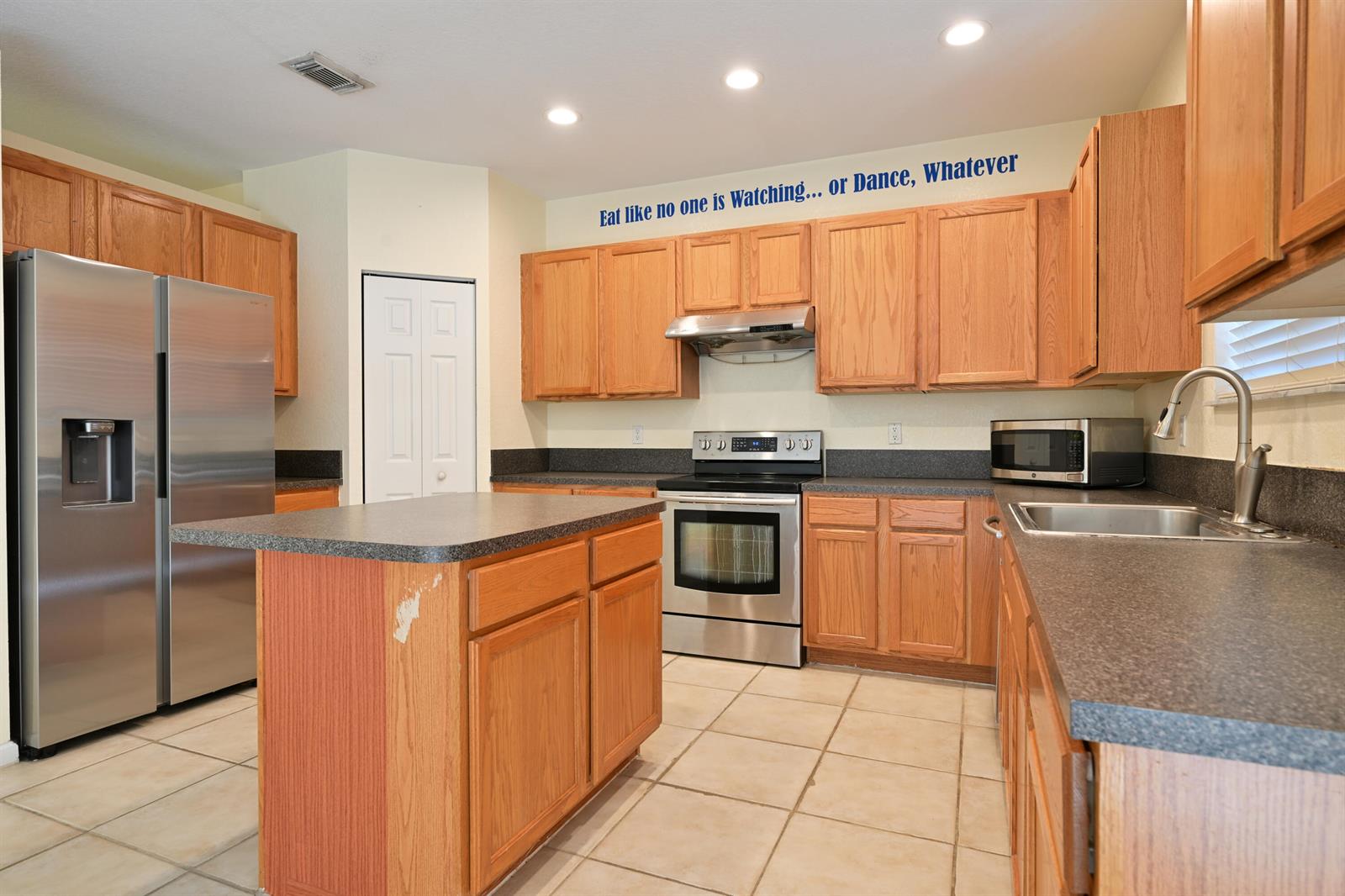 A kitchen with oak cabinets, stainless steel appliances, a center island, and tile flooring — 2789 S Evergreen Circle, Boynton Beach FL 33426, BOYNTON BEACH, FL