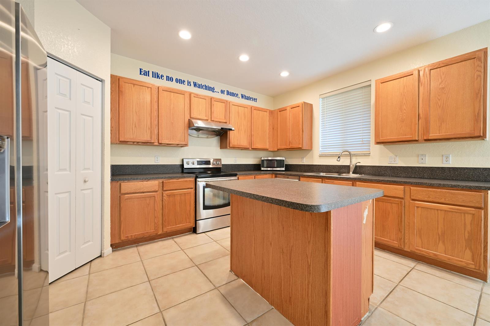 A kitchen with oak cabinets, dark countertops, a center island, and tile flooring — 2789 S Evergreen Circle, Boynton Beach FL 33426, BOYNTON BEACH, FL