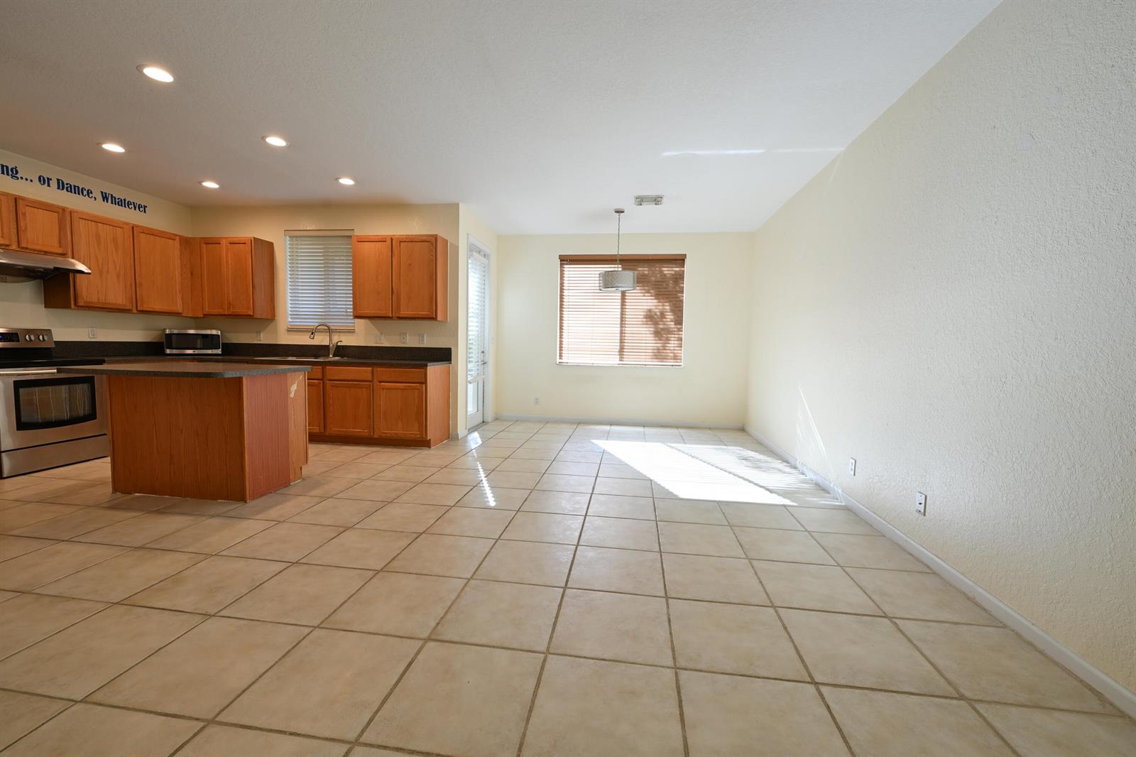 An open-concept kitchen and dining area features wood cabinets, tile flooring, and a large window — 2789 S Evergreen Circle, Boynton Beach FL 33426, BOYNTON BEACH, FL