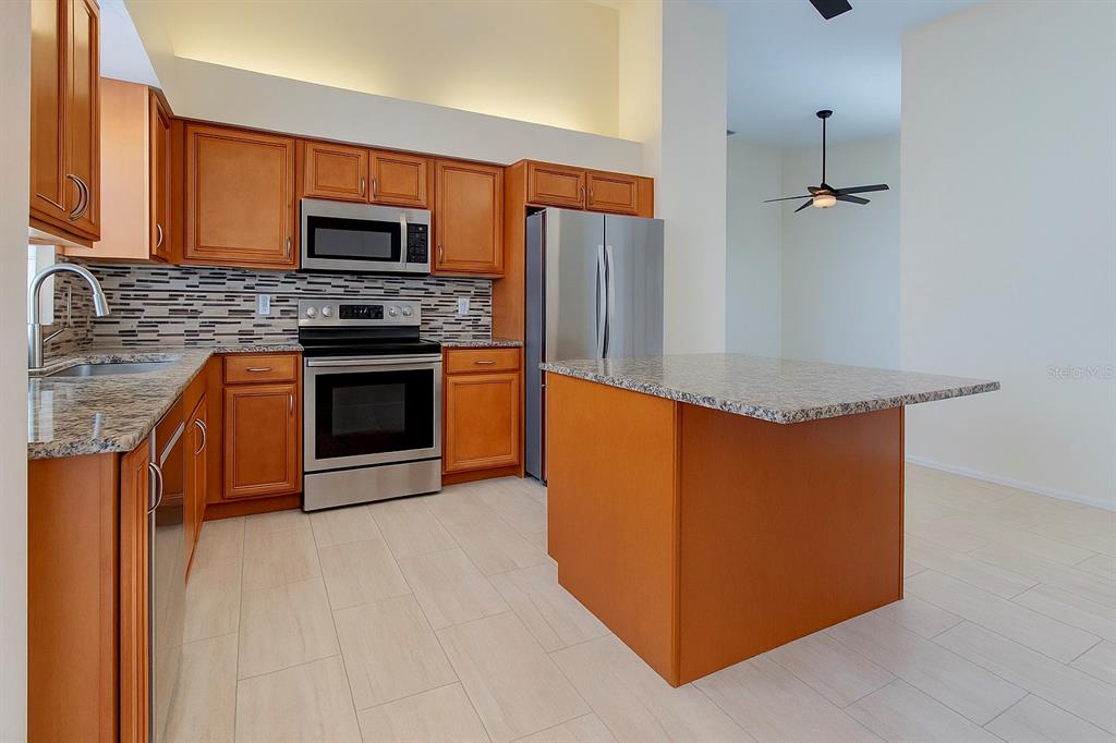 A kitchen features wood cabinets, granite countertops, stainless steel appliances, and a central island — 3867 DARSTON STREET, PALM HARBOR, FL