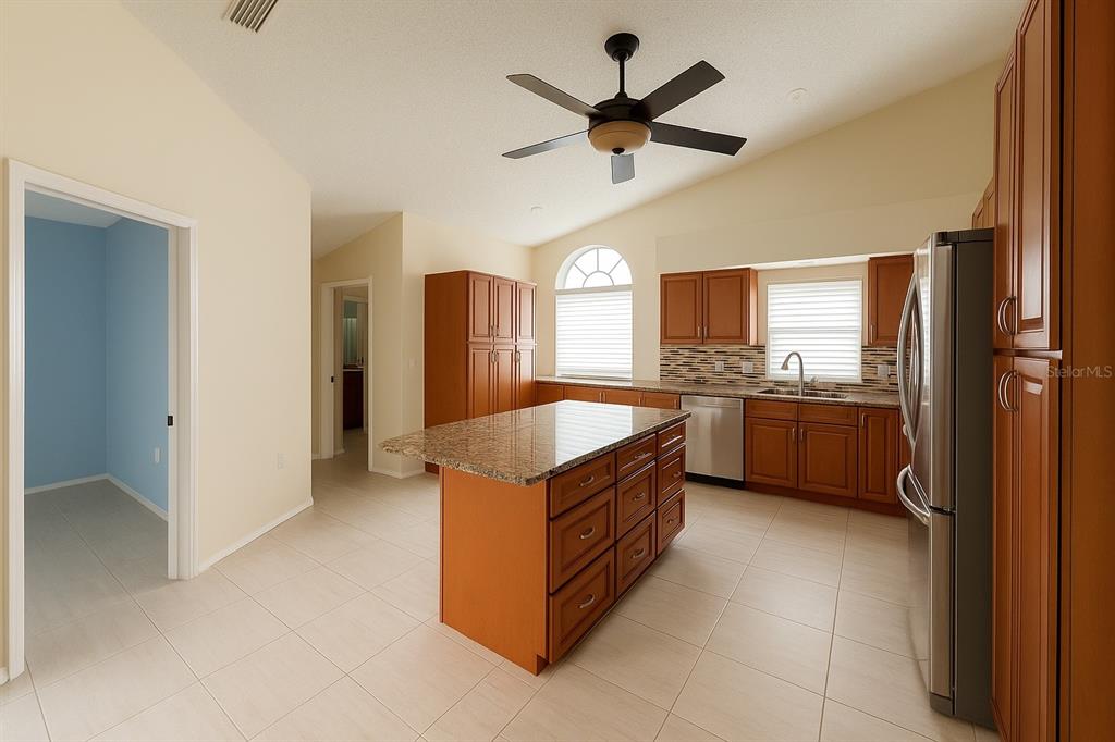 A kitchen with wood cabinets, granite countertops, a center island, and tile flooring — 3867 DARSTON STREET, PALM HARBOR, FL