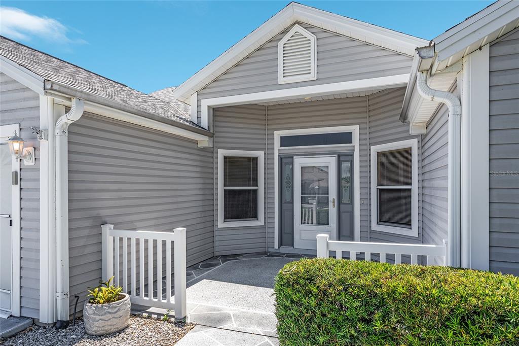 The exterior of a gray-sided house features a covered entryway with a white picket fence — 170 PALERMO PLACE, LADY LAKE, FL