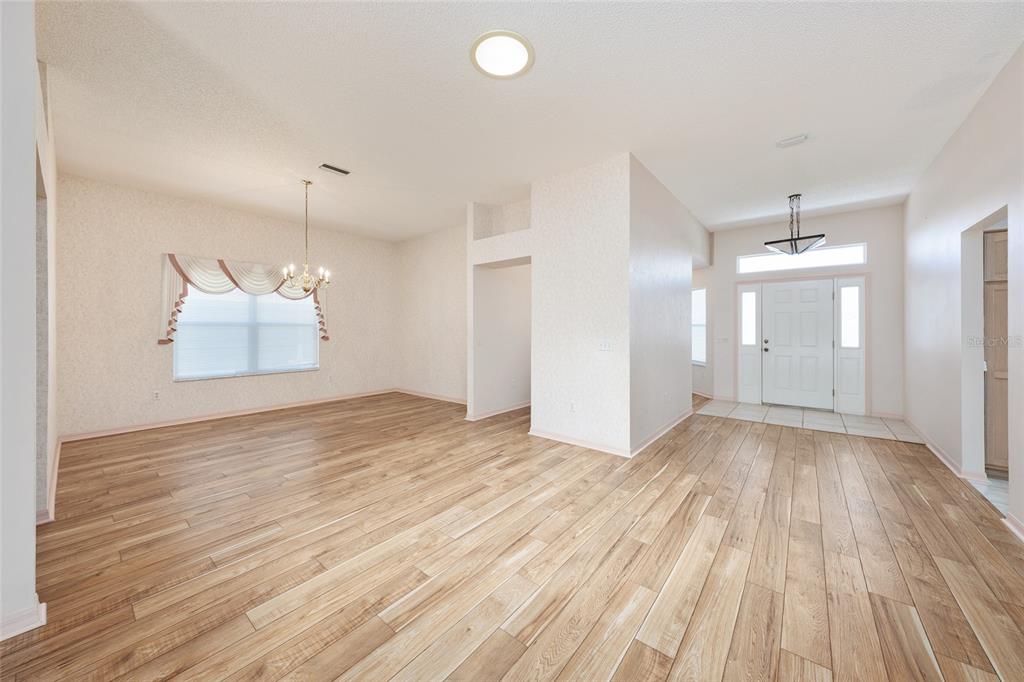 An open-concept dining area and entryway featuring light wood-look flooring and white walls — 170 PALERMO PLACE, LADY LAKE, FL