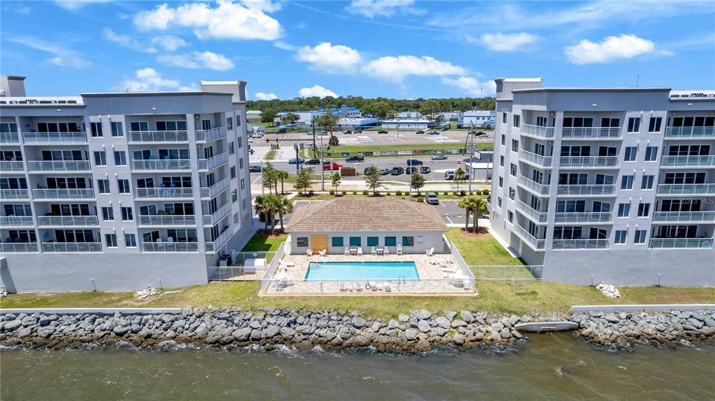 An aerial view shows two apartment buildings flanking a swimming pool and a small clubhouse — 1805 RIVERSIDE DRIVE UNIT 506, TITUSVILLE, FL