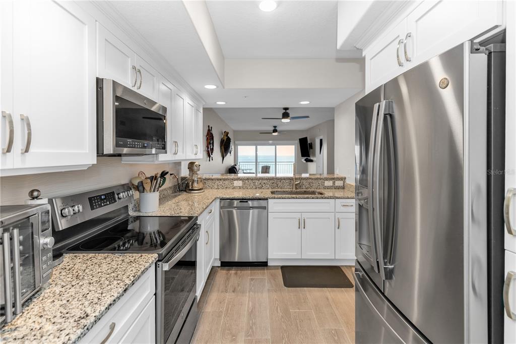 A kitchen with white cabinets, granite countertops, stainless steel appliances, and a view of the ocean — 1805 RIVERSIDE DRIVE UNIT 506, TITUSVILLE, FL