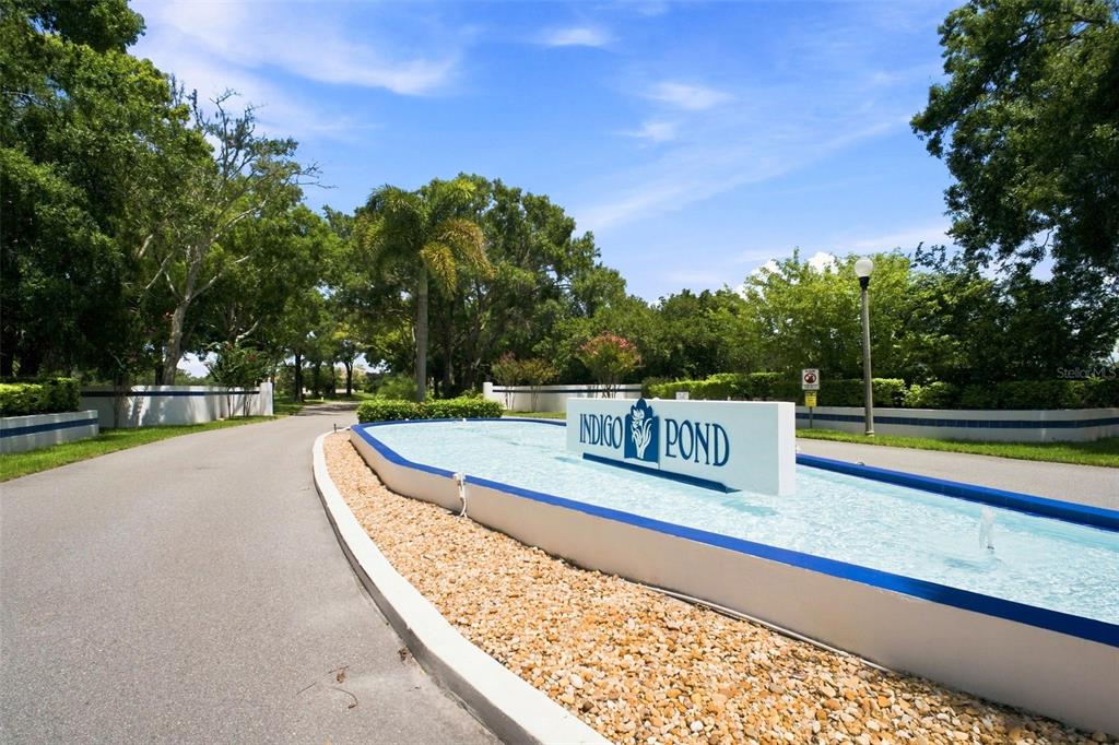 The entrance to the Indigo Pond community features a sign in a central water fountain — 3588 INDIGO POND DRIVE UNIT 12, PALM HARBOR, FL