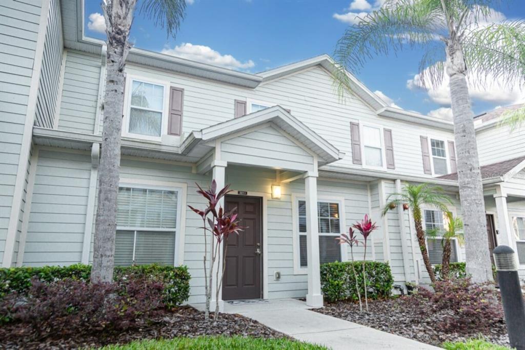 A two-story townhouse exterior with light blue siding, a covered entryway, and palm trees — 3211 GOLD LANE, KISSIMMEE, FL
