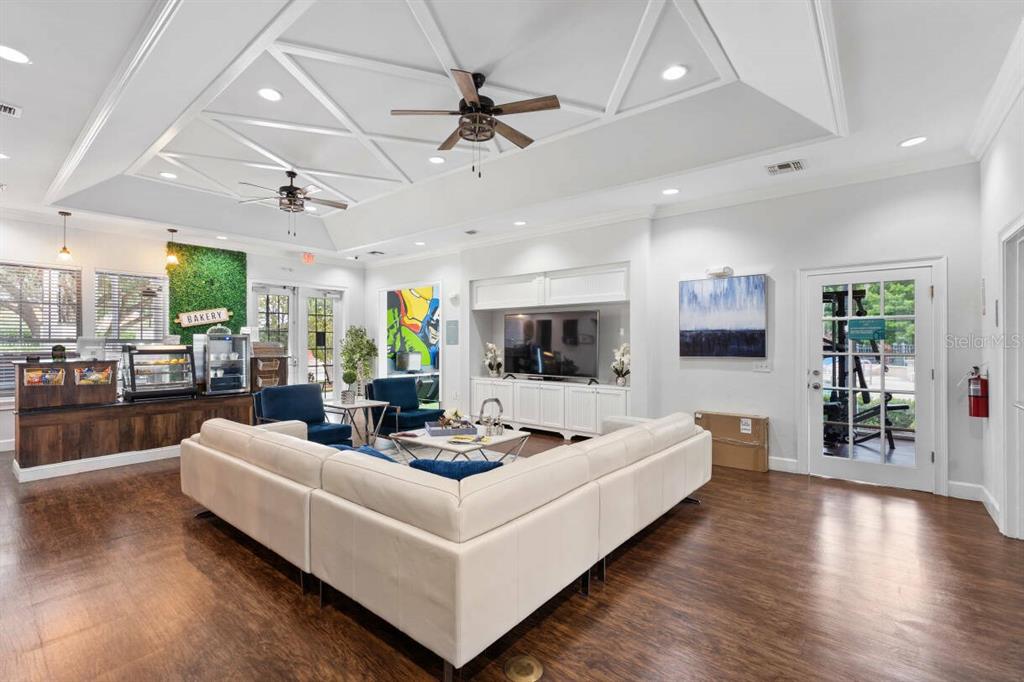 A spacious lounge area features a white sectional sofa, a television console, and a bakery counter — 3211 GOLD LANE, KISSIMMEE, FL
