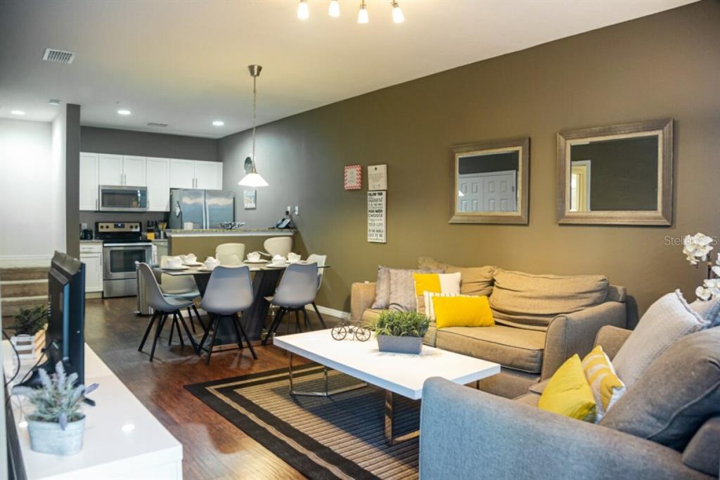 An open-concept living and dining area features a gray sofa, white coffee table, and kitchen — 3211 GOLD LANE, KISSIMMEE, FL