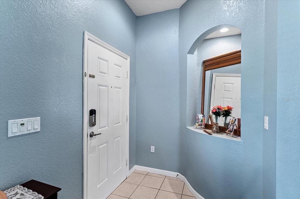 An entryway features a white door, light blue walls, tiled flooring, and an arched niche — 2886 OCONNELL DRIVE, KISSIMMEE, FL
