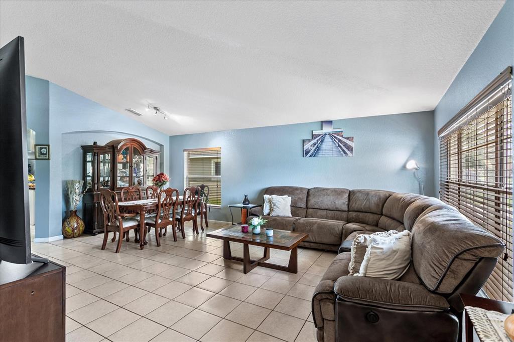 A living and dining room with tile floors, a brown sectional sofa, and wooden furniture — 2886 OCONNELL DRIVE, KISSIMMEE, FL