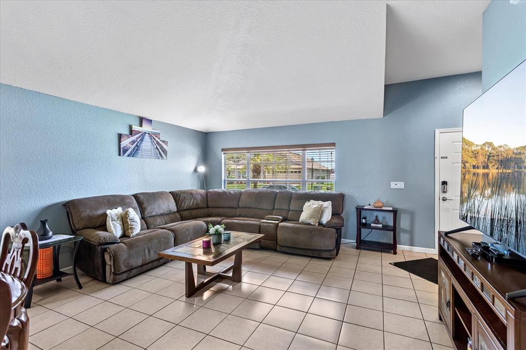 A living room features a large brown sectional sofa, a coffee table, and tile flooring — 2886 OCONNELL DRIVE, KISSIMMEE, FL