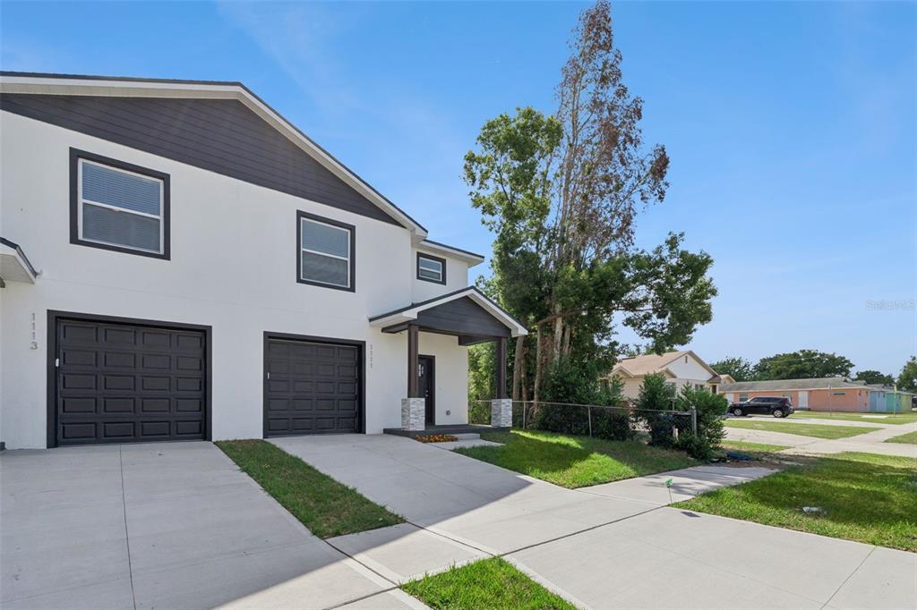 A two-story duplex with white stucco walls, dark trim, and two attached garages — 1111/1113 JEWEL AVENUE, LAKELAND, FL