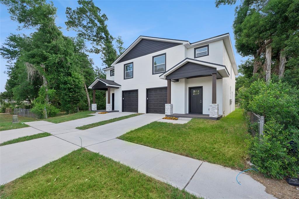 A two-story duplex with white stucco walls, dark trim, and two attached garages — 1111/1113 JEWEL AVENUE, LAKELAND, FL