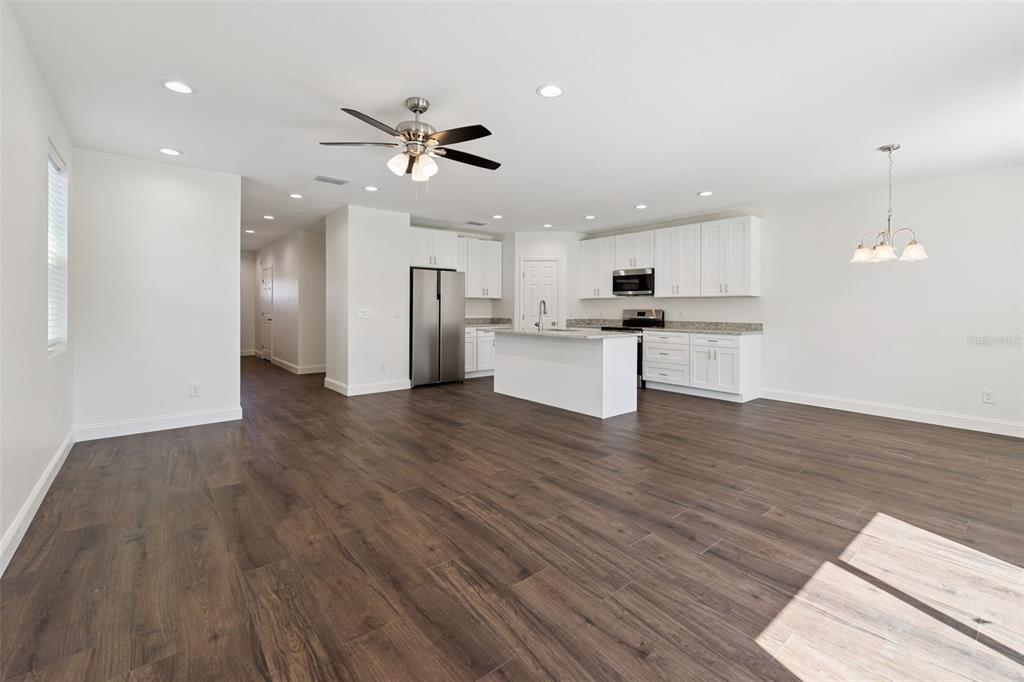 An open-concept kitchen and living area features white cabinetry, a center island, and wood-look flooring — 1111/1113 JEWEL AVENUE, LAKELAND, FL