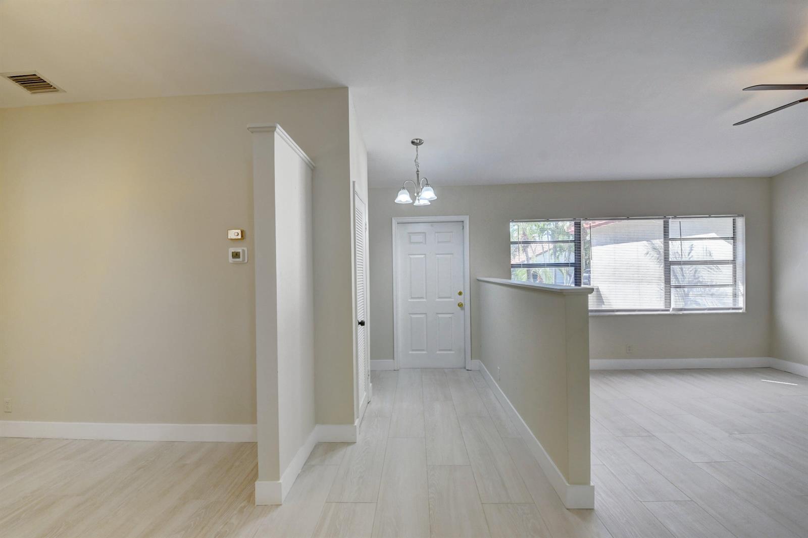 An entryway with light wood-look flooring leads to a white front door and living area — 7011 San Sebastian Circle, Boca Raton FL 33433, BOCA RATON, FL