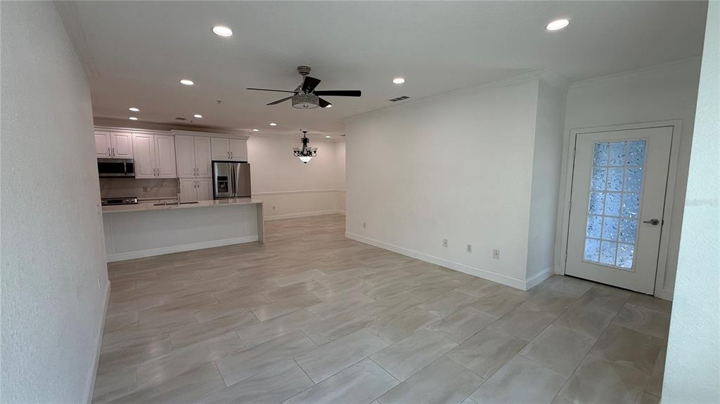 A modern kitchen features white cabinetry, a marble-topped island, and stainless steel appliances — 16303 ENCLAVE VILLAGE DRIVE UNIT 103, TAMPA, FL