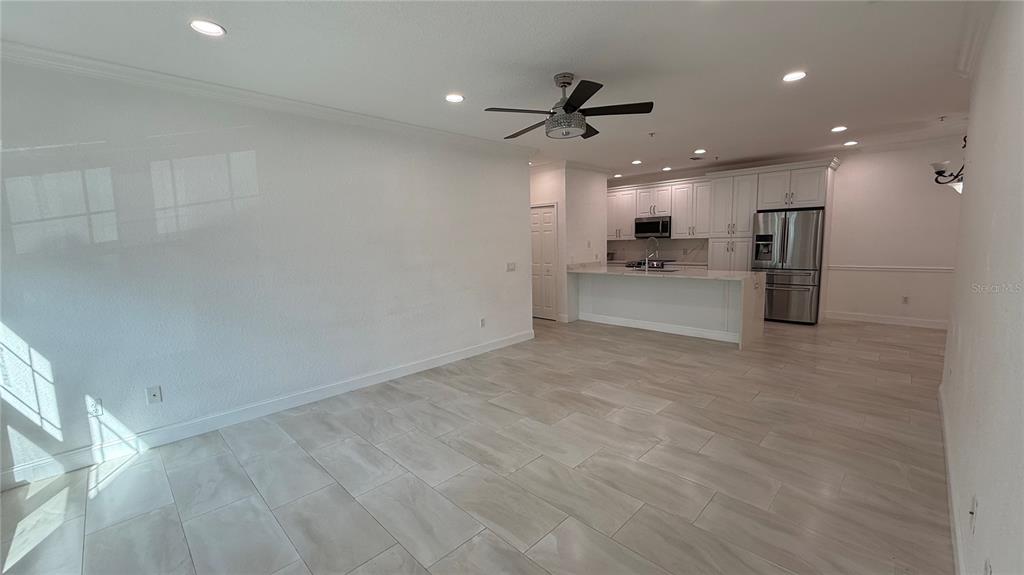 An open-concept living area features white cabinetry, a kitchen island, and light-colored tile flooring — 16303 ENCLAVE VILLAGE DRIVE UNIT 103, TAMPA, FL