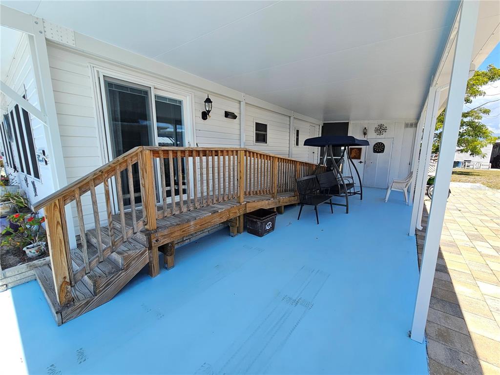 A covered patio with a wooden ramp, a swing, and a blue painted concrete floor — 205 VIA VENETO, VENICE, FL