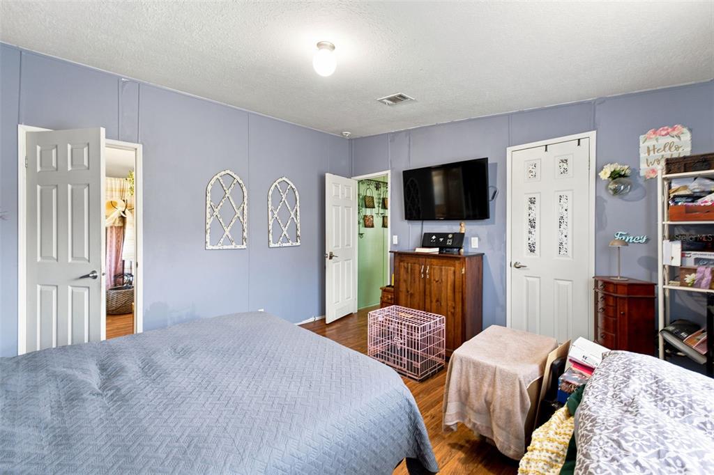 A bedroom features blue walls, a bed, a television on a wooden cabinet, and two doors — 4313 ORLANDO AVENUE, BROOKSVILLE, FL