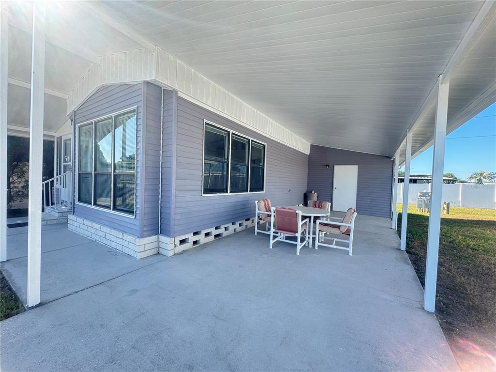 A covered concrete patio features a dining set beside a light blue mobile home — 35220 DODIE DRIVE UNIT 13, ZEPHYRHILLS, FL