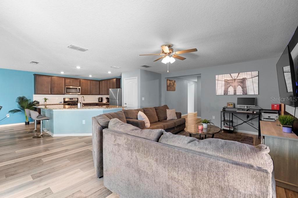 An open-concept living room and kitchen with wood-look flooring, gray walls, and a ceiling fan — 440 KENSINGTON VIEW DRIVE, WINTER HAVEN, FL