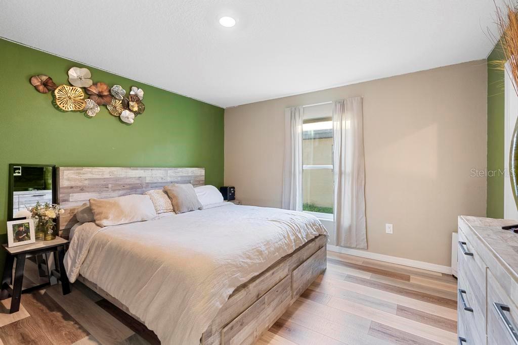 A bedroom features a green accent wall, a wood-plank headboard, and light wood-look flooring — 440 KENSINGTON VIEW DRIVE, WINTER HAVEN, FL