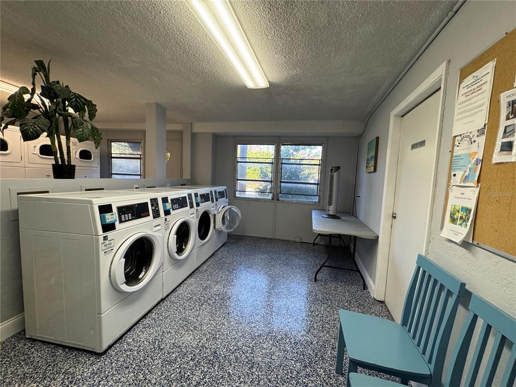 A laundry room features white front-load dryers, a folding table, and blue chairs — 3315 58TH AVENUE S UNIT 201, ST PETERSBURG, FL
