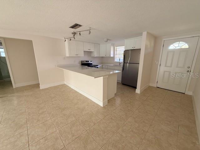 A kitchen features white cabinets, stainless steel appliances, a breakfast bar, and tiled flooring — 600 RUSSELL STREET, LONGBOAT KEY, FL