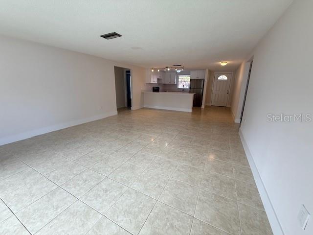 An open-concept living area features light-colored tile flooring and a kitchen with white cabinetry — 600 RUSSELL STREET, LONGBOAT KEY, FL