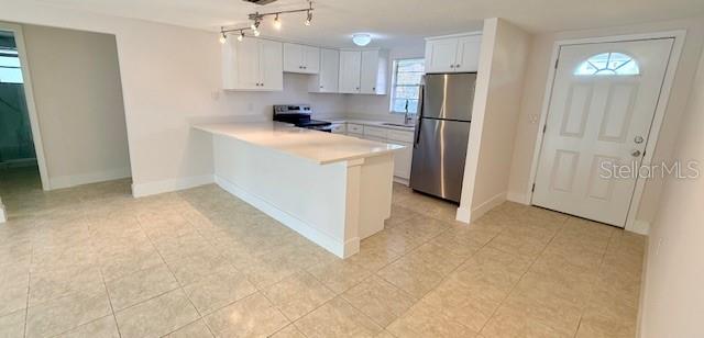 A kitchen features white cabinets, stainless steel appliances, a peninsula island, and light-colored tile flooring — 600 RUSSELL STREET, LONGBOAT KEY, FL
